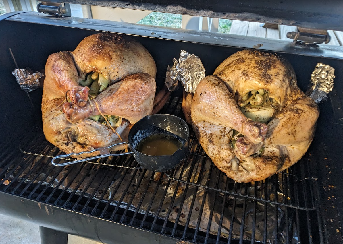 Two whole turkeys cooking on a smoker